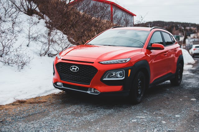 Red Hyundai SUV parked on a gravel road in snowy conditions — front and side view