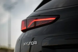 Close-up view of the rear section of a black Hyundai vehicle, featuring a modern red taillight design against a blurred outdoor background.