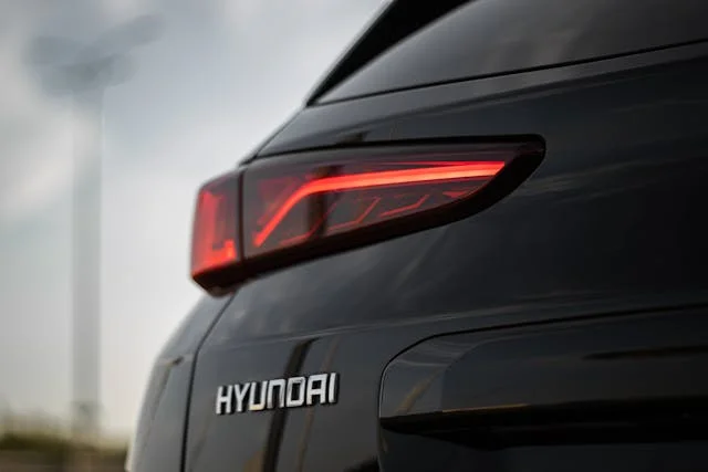 Close-up view of the rear section of a black Hyundai vehicle, featuring a modern red taillight design against a blurred outdoor background.